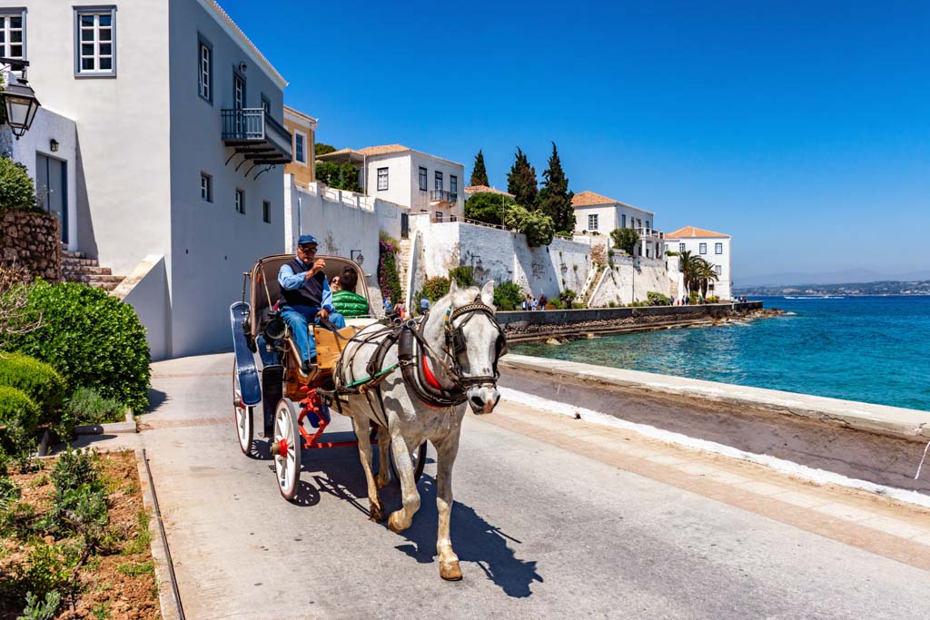 A young couple enjoys a ride by the seaside, with a horse carriage in Spetses near Athens